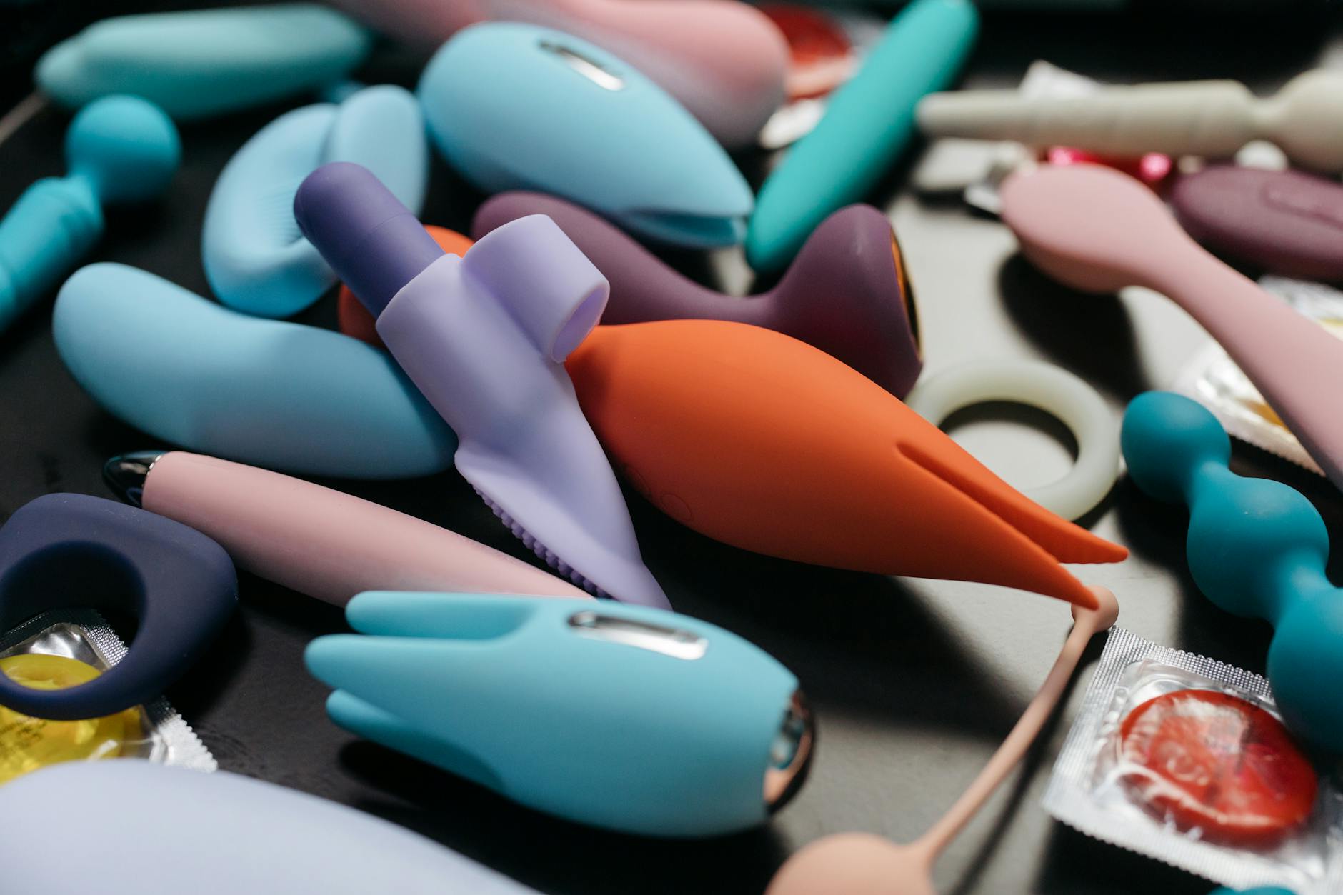 Close-up of vibrant adult toys including blue and pink clitoral vibrators in a minimalist arrangement.