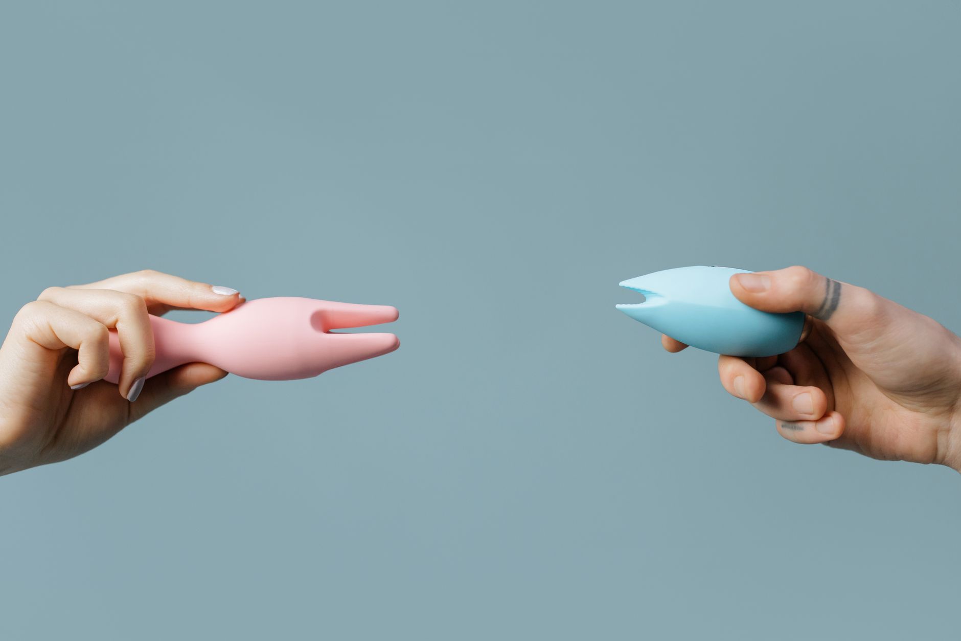 Two hands holding pink and blue silicone vibrators, representing self-discovery and reconnection after time apart