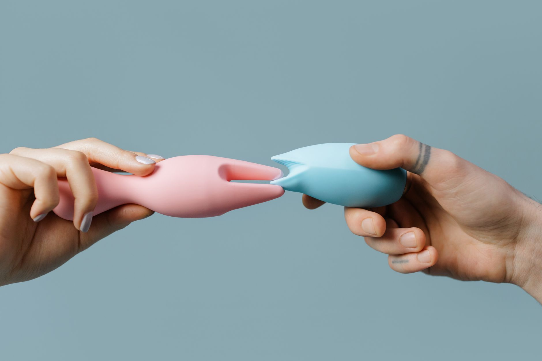 Hand reaching over a variety of colorful clitoral vibrators arranged on a table